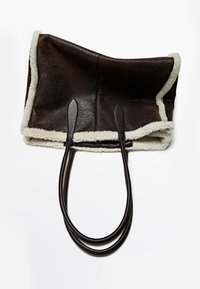 Bruine leren shopper met een zachte witte schapenvachtboord en twee lange bruine leren handvatten, met een ruim, open ontwerp.