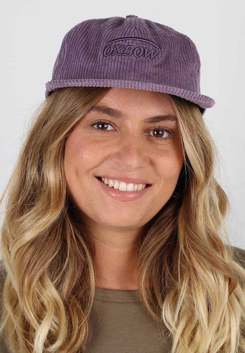 Casquette en velours côtelé violet avec logo "OXBOW" brodé, dotée d'une visière plate et d'un tissu texturé. Convient pour un usage décontracté.