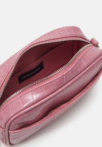 Borsa a mano in ecopelle rosa con effetto coccodrillo e chiusura con zip argentata. Interno foderato in tessuto morbido. Forma rettangolare compatta con una lieve texture.