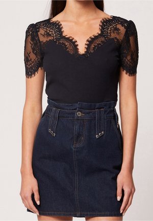 Haut noir en dentelle à manches courtes avec encolure festonnée, associé à une jupe en denim foncé taille haute avec passants pour ceinture et fermeture par boutons.