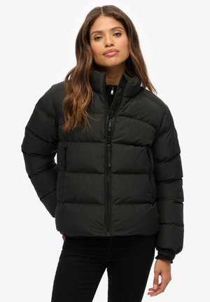Zwarte pufferjas met een hoge kraag, rits aan de voorkant en elastische manchetten. Bevat gestikte segmenten voor isolatie en een elegante uitstraling.