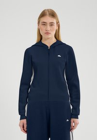 Felpa con cappuccio blu navy con cerniera e pannelli laterali bianchi. Caratterizzata da polsini e orlo a coste, con logo sul petto a sinistra. Tessuto morbido al tatto.