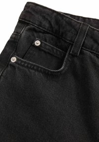 Primer plano de unos vaqueros de mezclilla negros, mostrando la cintura, el ojal del cinturón, el bolsillo delantero, el bolsillo para monedas y los remaches plateados sobre un fondo blanco.