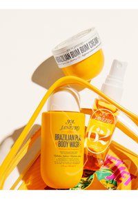 Gul Sol de Janeiro Brazilian Bum Bum Cream, Body Wash og 62 parfume mist i en klar gul taske på en hvid overflade.