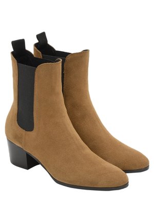 Paire de bottines en daim beige avec des panneaux latéraux élastiques noirs et des talons carrés bas.
