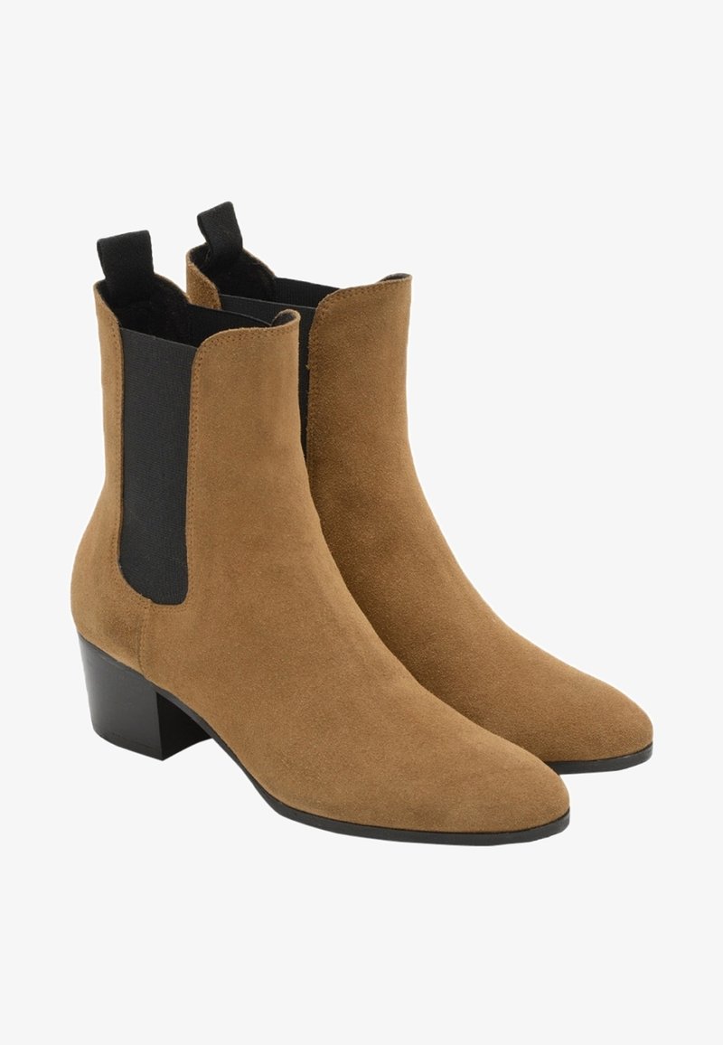 Paire de bottines en daim beige avec des panneaux latéraux élastiques noirs et des talons carrés bas.