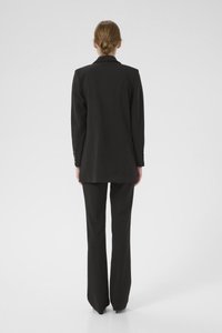 Svart skreddersydd blazer med lange ermer og flat krage, parret med matchende skreddersydde bukser, vist fra baksiden på en ensfarget bakgrunn.