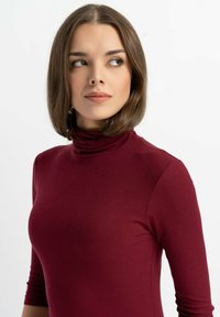 Bordowy, prążkowany golf o trzy czwarte rękawach, wykonany z miękkiego materiału, o dopasowanym fasonie i subtelnej fakturze.