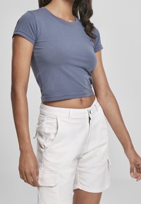 Crop top i blå bomullstyg, korta ärmar, rund halsringning, matchad med vita cargoshorts med sidofickor. Slät textur.