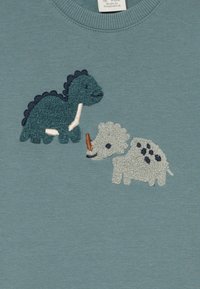 Blue sweatshirt featuring textured embroidery of a green dinosaur and a white triceratops, with stitched accents in darker blue and orange.