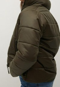 Olive green puffer jacket with a high collar, quilted design, and side pockets. Smooth, shiny fabric with a relaxed fit.