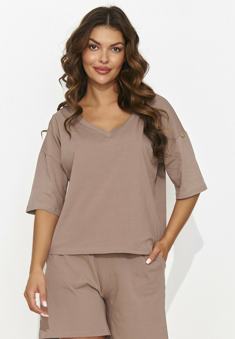 Jasnobrązowa bluzka V-neck z krótkimi rękawami, wykonana z miękkiego materiału. Posiada luźny krój oraz akcentowany guzik na rękawie. Zestawiona z pasującymi szortami.