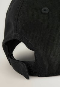Cappello nero con tessuto testurizzato, dotato di una visiera curva e di una fascia regolabile in Velcro sul retro, che mette in mostra dettagli di cucitura.