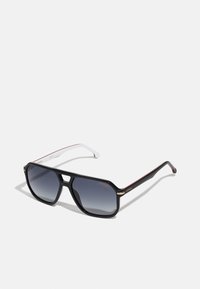 Ochelari de soare negri, supradimensionați, cu lentile gri degradé, design unghiular, accente aurii pe rame și brațe cu un model alb și roșu.