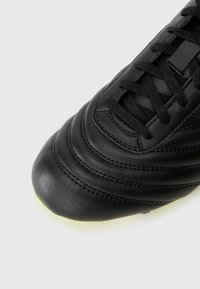 Black leather soccer shoe with stitched detail on the toe box, textured upper, and traditional lace closure. Slightly rounded toe shape.