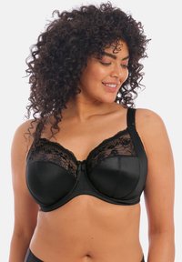 Zwarte bh met kantdetails langs de cups, een gladde satijnen afwerking, verstelbare bandjes en een kleine strikaccent in het midden.