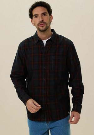 Zwarte en donkerrode geblokte flanellen shirt met een knoopsluiting aan de voorkant, lange mouwen en een borstzak, gecombineerd met lichtblauwe jeans.