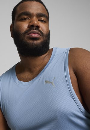 Světle modré sportovní tričko bez rukávů s texturovanou tkaninou a stříbrným logem PUMA, s kulatým výstřihem a volným střihem.