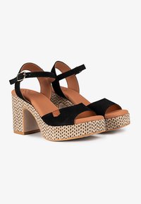 Sandalias de tacón alto de ante negro con base de yute trenzado, diseño de punta abierta, correa ajustable en el tobillo y plantilla en color marrón.