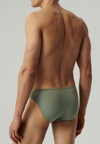 Męskie zielone slipy, bawełniany materiał, dopasowany fason, niski krój, gładka faktura, minimalistyczny styl, jednolity kolor bez wzorów czy akcentów.