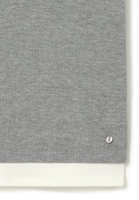 Tissu de sweat-shirt gris à côtes avec un ourlet texturé blanc et un petit logo en argent en bas à droite.