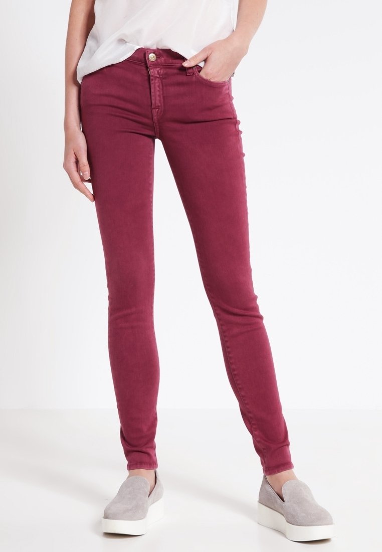 Burgundin väriset skinny-farkut, jotka on valmistettu puuvillavenytetystä kankaasta, joissa on sileä pinta, viisi taskua ja vetoketjukiinnitys. Yhdistetty harmaisiin liukuviin kenkiin.