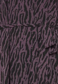 Tissu à motifs violet et noir avec un design à imprimé animal ondulé, comportant une ceinture en tissu nouée à la taille et une surface texturée.
