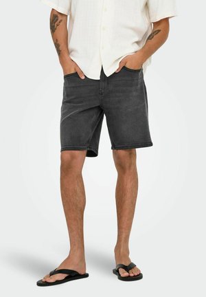 Donkergrijze denim shorts met een rechte snit, vijf zakken en een gladde textuur, gecombineerd met zwarte teenslippers en een lichtgewicht shirt.