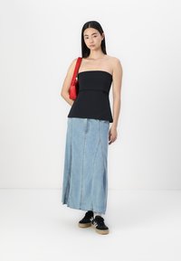 Must mustriba peplum disainiga must tops, millele on kombineeritud heledast sinisest denimpikast, millel on vertikaalsed õmblused. Aksessuaariks on punane käekott ja mustad spordijalatsid.