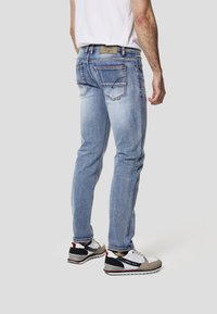 Lyseblå denimjeans med en slank pasform, fem lommer og kontrastsøm. Har en læderlap på linningen.