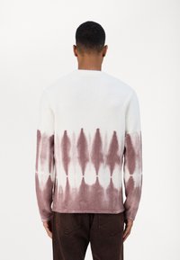 Udu, ümmarguse kaelusega sviiter, millel on valge ülemine osa ja roosa tie-dye muster. Ribidega mansetid ja alläär. Pehme tekstuur, vabaajakohane lõige.
