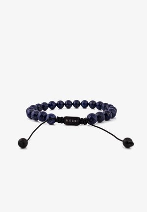 Kék lápisz lazuli gyöngy karkötő fekete állítható zsinórral. Kör alakú gyöngyökkel és "AKITSUNE" felirattal gravírozott fém címkével rendelkezik.