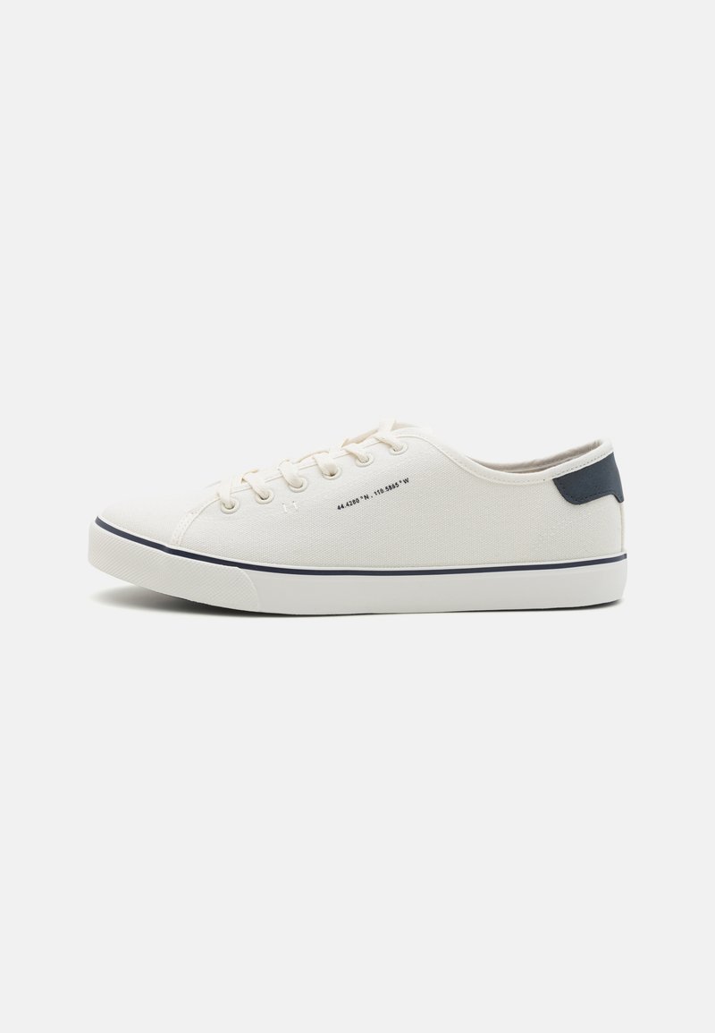 Zapatillas de lona en color blanco roto con detalles en azul marino, que cuentan con puntera redonda, diseño de cordones y suela de goma texturizada. Estética simple y limpia.