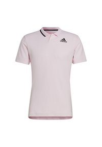 Polo shirt rose clair en tissu texturé, avec un col noir et un logo Adidas noir brodé sur la poitrine gauche.
