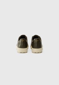 Oliwkowe skórzane sneakersy z okrągłym noskiem, wyściełanym kołnierzem i beżową gumową podeszwą. Posiadają wytłoczone logo na pięcie.