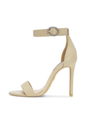 Beige sandaal met hoge hak en een dunne enkelband met een glinsterende ovale gesp, open teen en naaldhak.
