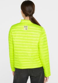 Neon green puffer jacket with horizontal stitching, high collar, and a label at the back. Smooth texture and lightweight design.
