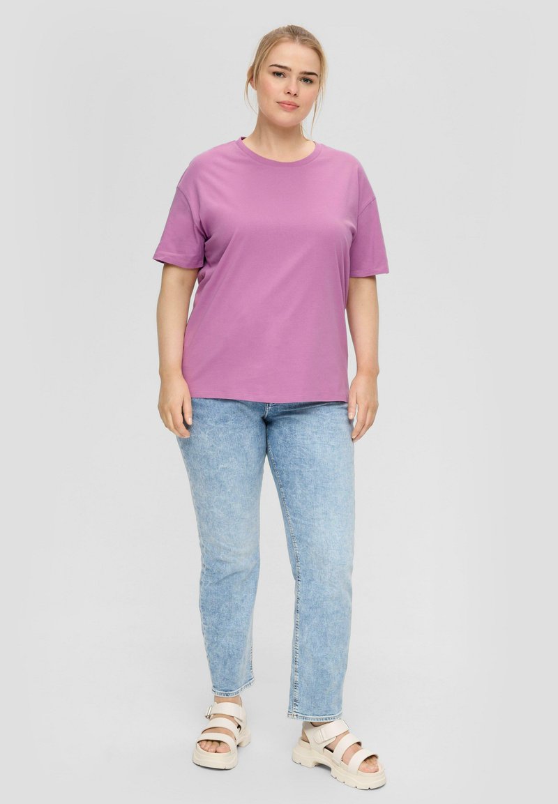Paarse korte mouwen t-shirt gecombineerd met lichtblauwe spijkerbroek en witte sandalen, met een ontspannen pasvorm en een zachte textuur.