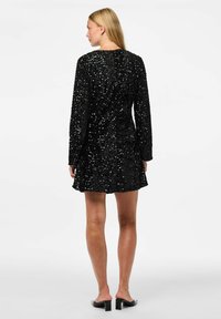 Vestido negro de lentejuelas con mangas largas, cuerpo ajustado y falda acampanada. Textura suave, hasta la rodilla, cierre de cremallera en la parte posterior.