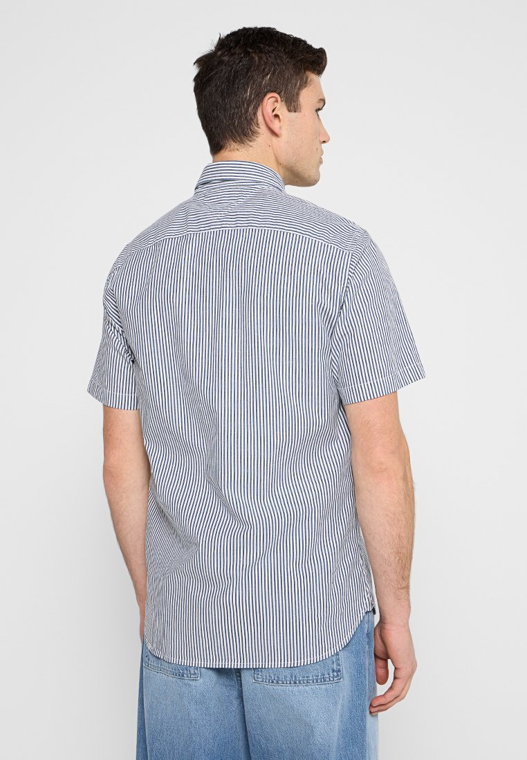 Chemise à manches courtes avec col, présentant des rayures verticales bleues et blanches, en tissu léger avec une coupe droite à l'ourlet.