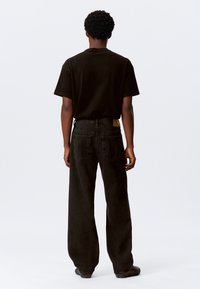 Black cotton T-shirt and dark denim jeans, featuring a straight-leg cut, five pockets, and a visible back label. Matte texture, casual design.
