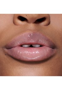 Glanzende, lichtroze lippen met een subtiele glans, die een natuurlijke textuur en gladheid tonen, tegen een achtergrond van een warme huidskleur.