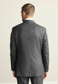 Grauer, strukturierter Anzugjacke mit Kerbkragen, einem einzelnen Rückenschlitz und geknöpften Manschetten, von hinten gesehen. Maßgeschneiderte Passform.