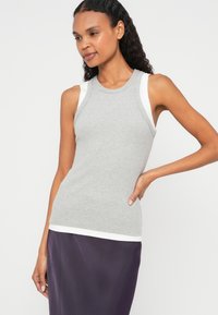 Top de alças cinzento com nervuras, com detalhes brancos nas costuras dos ombros e na bainha, design ajustado, combinado com uma saia roxa, textura suave do tecido.