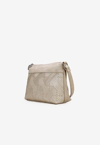 Bolso cruzado de cuero beige con patrón geométrico en relieve, cierre de cremallera, correa ajustable y textura suave en el panel superior.