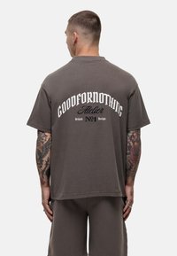 T-shirt grigio oversize con la scritta "GOODFOR NOTHING" stampata in bianco sulla parte posteriore, caratterizzata da un collo rotondo e maniche corte.