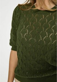 Olivgrön stickad tröja med ett öppet mönster, korta ärmar och ribbad fåll, med texturerad detaljer genom hela plagget.