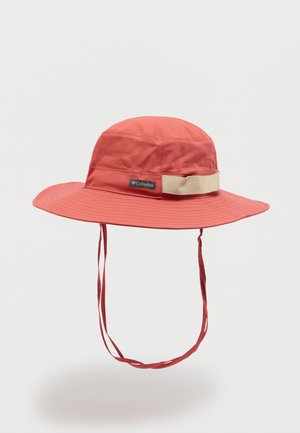 Sombrero rojo de ala ancha para exteriores con correas para la barbilla y banda beige, con un logo de Columbia sobre un fondo blanco liso.