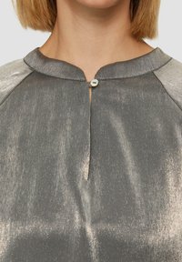 Grijze metallic blouse met een ronde kraag, voorzien van een knoopsluiting bij de hals en een iets gestructureerde, gladde stof.