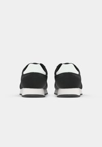 Black athletic shoes with a textured upper, white accents on the heel, and a gray rubber sole, featuring a rounded shape and lace closure.